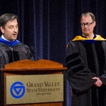 A faculty member listens as a fellow faculty member gives remarks